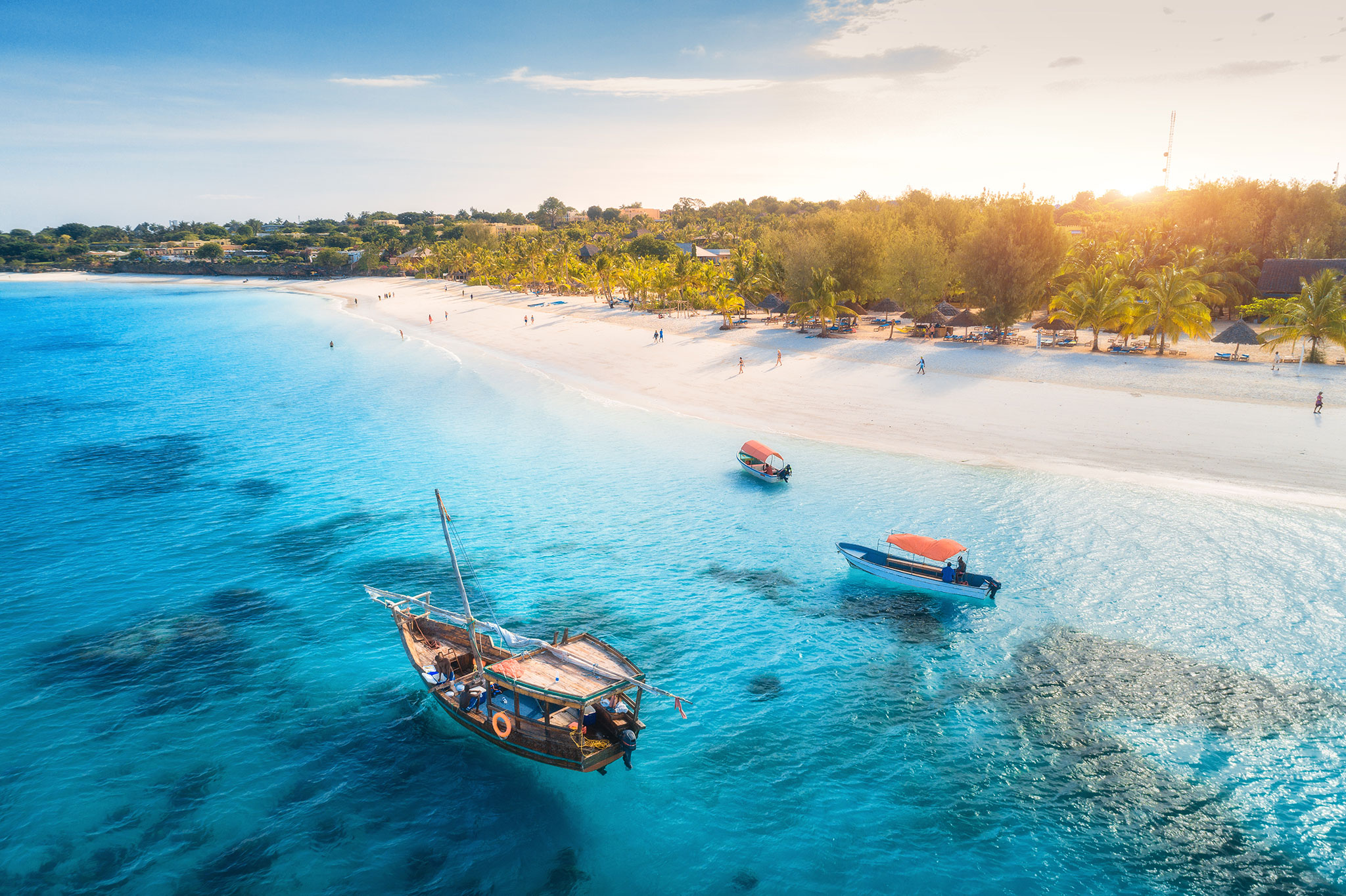 aerial-view-of-the-fishing-boats-on-tropical-sea-coast-with-sandy-beach-at-sunset Traumstrand auf Sansibar, wählen Sie die beste Reisezeit für die Serengeti so, dass Sie einen Badeurlaub anhängen können