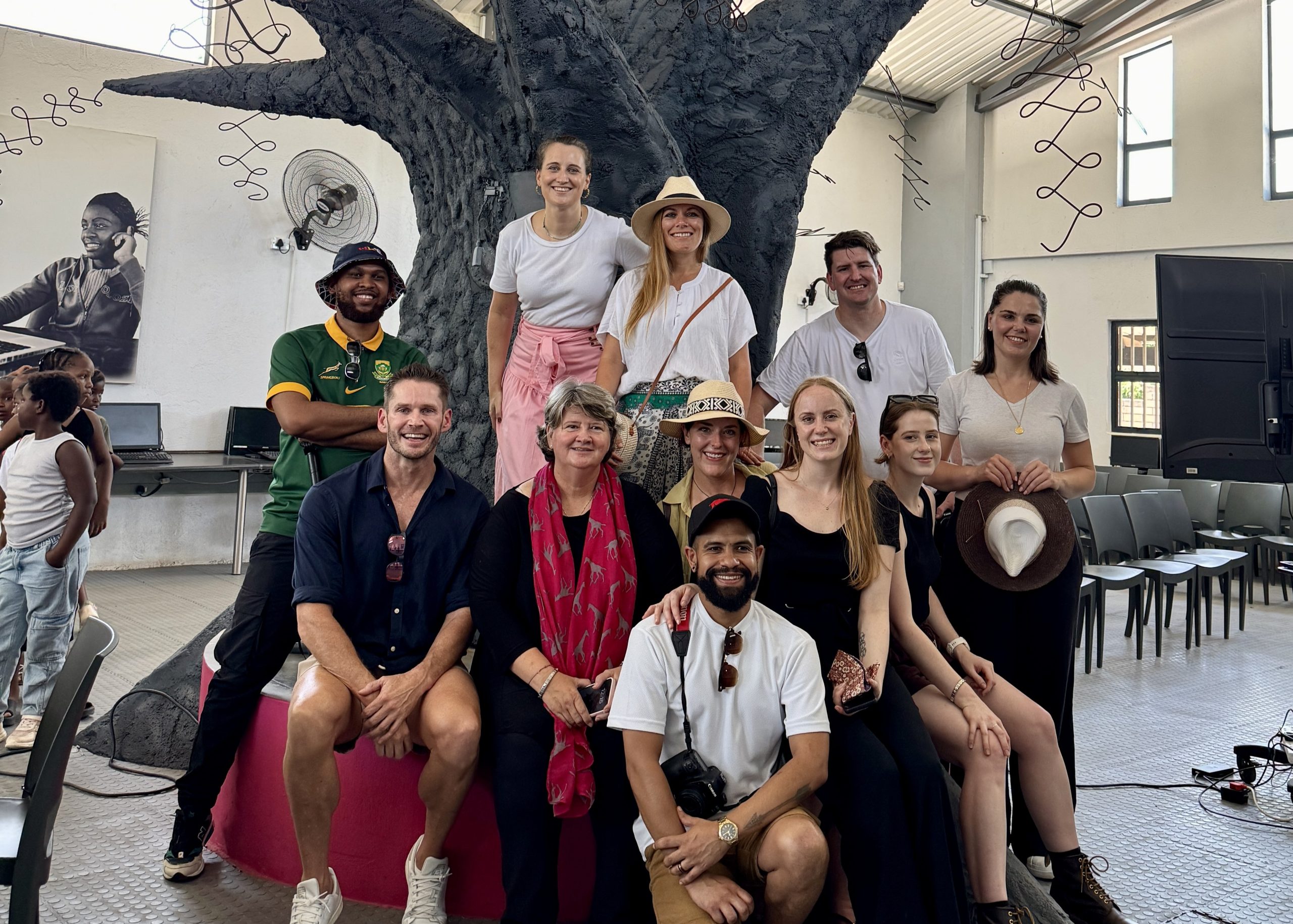 Brad-Mitchell-GWF-Visit-Group-photo-2 A group of smiling individuals from the Rhino Africa marketing team pose together in front of the striking tree sculpture at GWF, capturing a moment of connection and shared purpose.