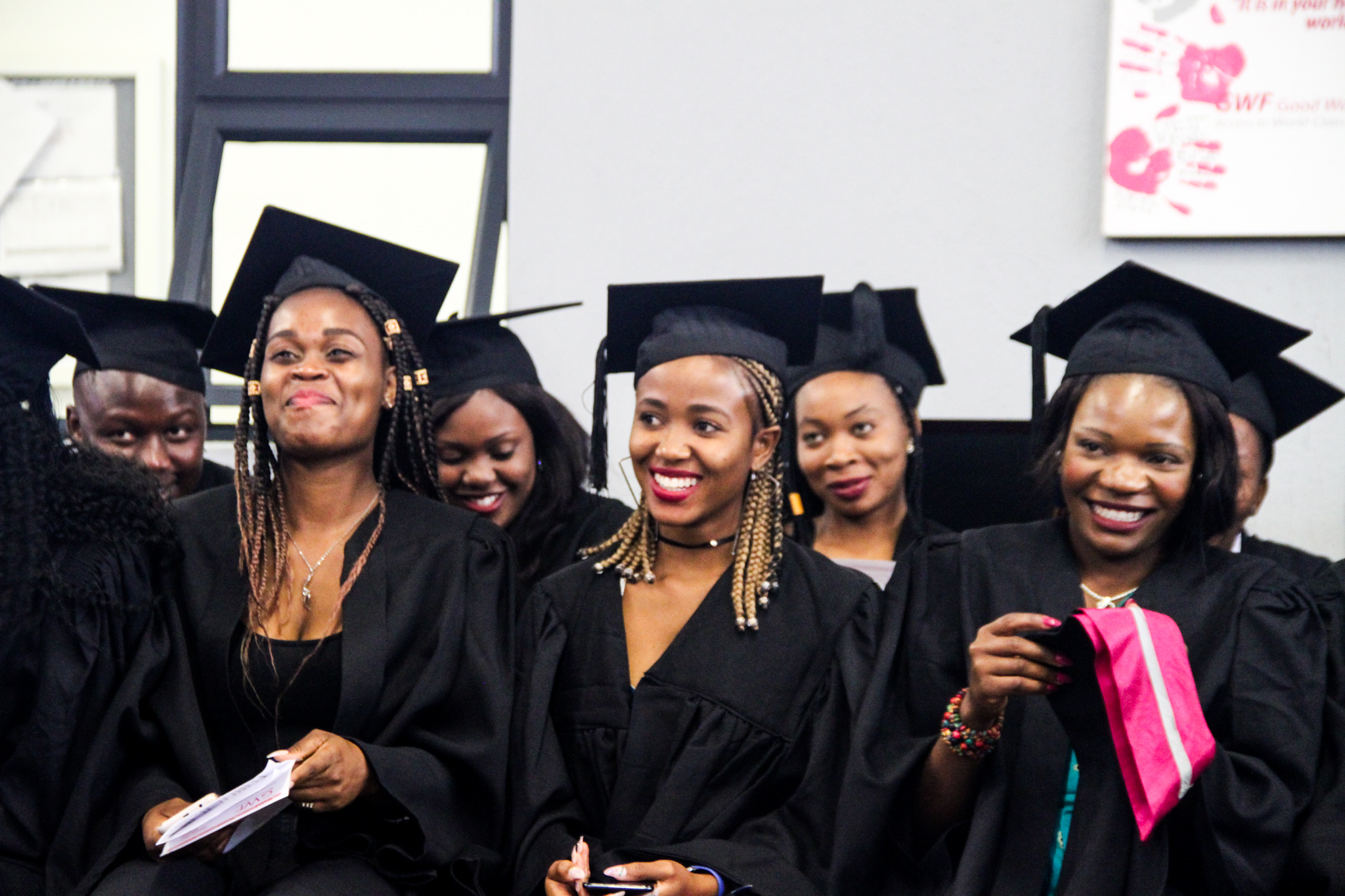 Good-Work-Foundation-Graduates A group of graduates dressed in black gowns and mortarboards sit together, their faces glowing with pride, joy, and anticipation as they celebrate their achievement.